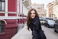 Beautiful smiling young lady in black coat posing in the city Royalty Free Stock Photo