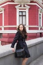 Beautiful smiling young lady in black coat posing in the city Royalty Free Stock Photo