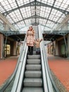 Beautiful smiling young mother holding her little son by hand while standing on escalator at shopping mall Royalty Free Stock Photo