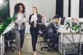 Beautiful smiling young multiracial businesswomen holding papers and walking