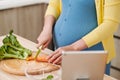 Beautiful smiling young pregnant woman preparing healthy food with lots of fruit and vegetables at home kitchen Royalty Free Stock Photo