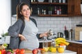 Pregnant woman preparing healthy food with lots of fruit and vegetables at home Royalty Free Stock Photo