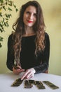 Beautiful young woman in a black velvet dress lays out cards on the table Royalty Free Stock Photo