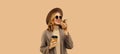 Beautiful smiling young woman with coffee cup holding cellphone using voice command recorder, assistant or takes calling wearing Royalty Free Stock Photo