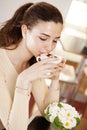 Beautiful smiling young woman drinking a cup of coffee at the cafe coffee bar, ice cream shop and pastry shop. She enjoying his Royalty Free Stock Photo