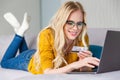 beautiful smiling young woman in eyeglasses holding credit card and using laptop Royalty Free Stock Photo