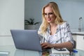 beautiful smiling young woman in eyeglasses using laptop while working