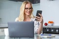 beautiful smiling young woman in eyeglasses using smartphone and laptop