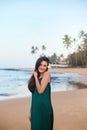 Beautiful smiling young woman in green dress on beach over sea and blue sky background. Royalty Free Stock Photo