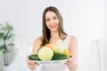 Beautiful smiling young woman holding a plate of fresh fruits, apple, pear, lemon, grapefruit, kiwi and cucumber Royalty Free Stock Photo