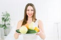 Beautiful smiling young woman holding a plate of fresh fruits, apple, pear, lemon, grapefruit, kiwi and cucumber Royalty Free Stock Photo