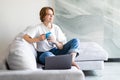 Beautiful young woman with laptop and cup of coffee on the sofa Royalty Free Stock Photo