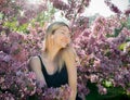 Beautiful smiling young woman near the blossoming spring tree. Portrait of pretty blond girl with long hair in pink flowers. Royalty Free Stock Photo