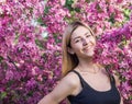 Beautiful smiling young woman near the blossoming spring tree. Portrait of pretty blond girl with long hair in pink flowers. Royalty Free Stock Photo