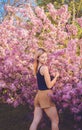 Beautiful smiling young woman near the blossoming spring tree. Portrait of pretty blond girl with long hair in pink flowers. Royalty Free Stock Photo