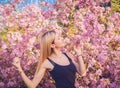 Beautiful smiling young woman near the blossoming spring tree. Portrait of pretty blond girl with long hair in pink flowers. Royalty Free Stock Photo