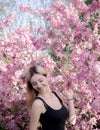 Beautiful smiling young woman near the blossoming spring tree. Portrait of pretty blond girl with long hair in pink flowers. Royalty Free Stock Photo