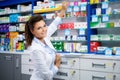 Beautiful smiling young woman pharmacist doing his work in pharmacy. Royalty Free Stock Photo