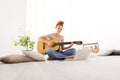 Beautiful smiling young woman playing guitar with computer, lear Royalty Free Stock Photo