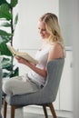 beautiful smiling young woman reading book while sitting in cozy chair Royalty Free Stock Photo