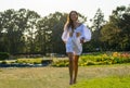 Beautiful smiling young woman runs in white clothes in a meadow with a flowers at sunset Royalty Free Stock Photo