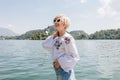 beautiful smiling young woman in sunglasses standing near majestic mountain lake Royalty Free Stock Photo