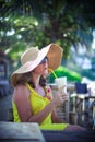 Beautiful smiling young woman in sunglasses wearing hat with a cocktail at the beach cafe Royalty Free Stock Photo