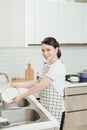 Beautiful smiling young woman washing the dishes in modern white kitchen Royalty Free Stock Photo