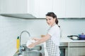 Beautiful smiling young woman washing the dishes in modern white kitchen Royalty Free Stock Photo