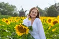 Beautiful smiling young woman in a white shirt stands in the field among sunflowers Royalty Free Stock Photo