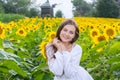 Beautiful smiling young woman in a white shirt stands in the field among sunflowers at a rural landscape background Royalty Free Stock Photo