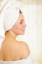 Beautiful smiling young woman with a white towel covering her head is posing, back side Royalty Free Stock Photo