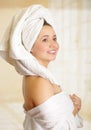 Beautiful smiling young woman with a white towel covering her head is posing with both hands in her body towel Royalty Free Stock Photo