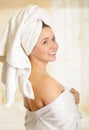 Beautiful smiling young woman with a white towel covering her head is posing with one hand in her body towel Royalty Free Stock Photo