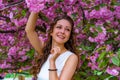 Beautiful smily girl with curly hair in white dress in the garden in pink blossom flowers Royalty Free Stock Photo