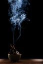 beautiful smoke and lighting of paper burned in ceramic bow against blackness background