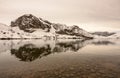 Beautiful snow-covered mountain by the lakeshore at a pinkish-gray sunset