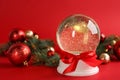 Beautiful snow globe, Christmas balls and fir branches on red background Royalty Free Stock Photo