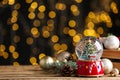 Beautiful snow globe and Christmas decor on wooden table against blurred festive lights. Space for text Royalty Free Stock Photo