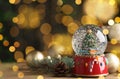 Beautiful snow globe and Christmas decor on wooden table against blurred festive lights, space for text. Bokeh effect Royalty Free Stock Photo