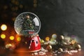 Beautiful snow globe with Christmas tree on dark background, bokeh effect. Space for text Royalty Free Stock Photo