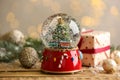 Beautiful snow globe with Christmas tree on wooden table against blurred festive lights Royalty Free Stock Photo