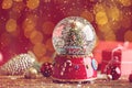Beautiful snow globe with Christmas tree on wooden table against red background. Bokeh effect Royalty Free Stock Photo