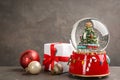 Beautiful snow globe, gift box and Christmas balls on grey table