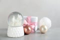 Beautiful snow globe, gift box and Christmas decor on light grey stone table