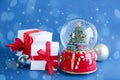 Beautiful snow globe, gift boxes and Christmas balls on blue background. Bokeh effect Royalty Free Stock Photo