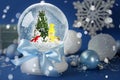 Beautiful snow globe with snowmen and Christmas tree on blue background. Bokeh effect Royalty Free Stock Photo
