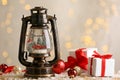 Beautiful snow globe in vintage lantern, gift boxes and Christmas decor on table against blurred festive lights Royalty Free Stock Photo