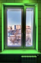 Beautiful snow view from the green neon illuminated window to the blue winter park and residential area Royalty Free Stock Photo