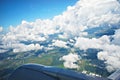 Beautiful snow-white clouds and a view of the green lands from the window of the airplane and part of the wing